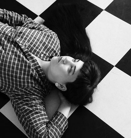 black and white photo of Melissa laying on the floor with hand behind her head. Photo by Alyson Hardwick